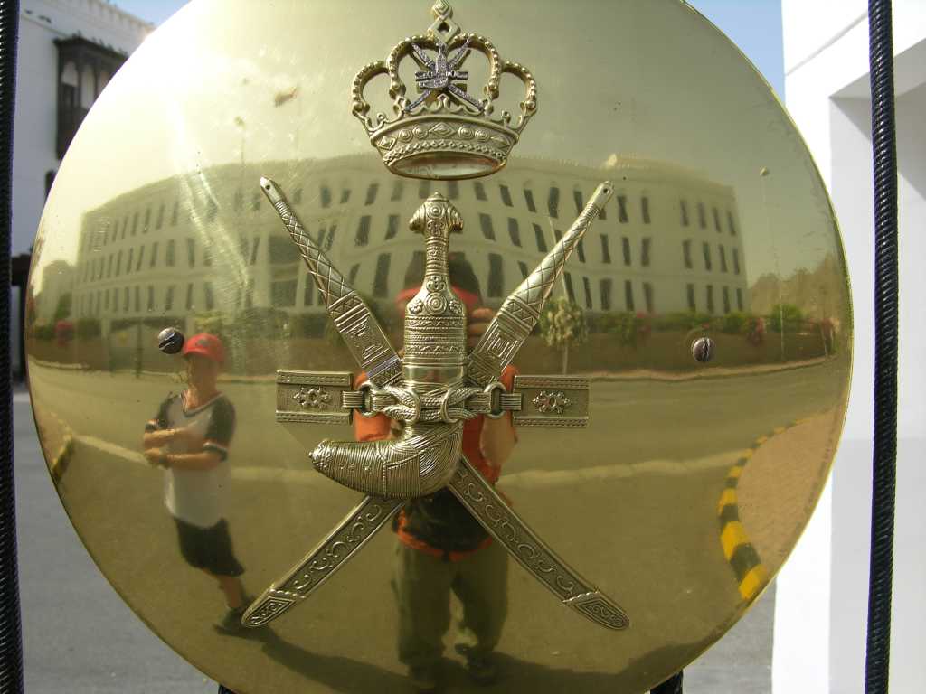 Muscat 02 Muscat 06 Sultan Qaboos Al-Alam Palace Gate With Khanjar Dagger Here is the National Emblem of Oman, consisting of a khanjar dagger in a sheath that is superimposed upon two crossed swords, shining on the gates to the Sultan Qaboos Al-Alam Palace.